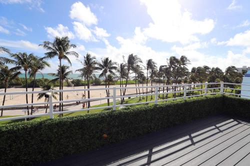 a view of a beach with palm trees and a white fence at Ocean Drive Rooftop Suite with Ocean Views & Terrace in Miami Beach