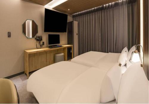 a hotel room with two white beds and a television at Day & Night Hotel in Incheon