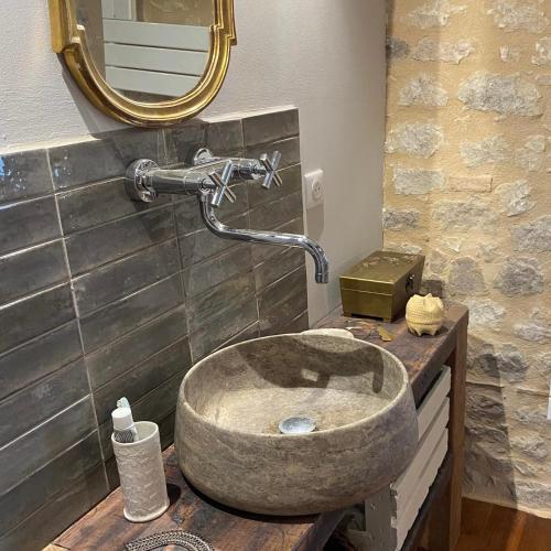 une salle de bain avec un lavabo en pierre et un miroir dans l'établissement Les vins de Rouyré - Maison, 4 pers, grand jardin, bain nordique, à Sainte-Cécile-du-Cayrou