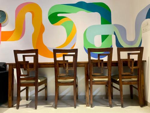 a table with four chairs in front of a mural at HOSHTEL99 - LUX - Stay, Cowork and Cafe - Luxurious Twin Bungalow in Pune