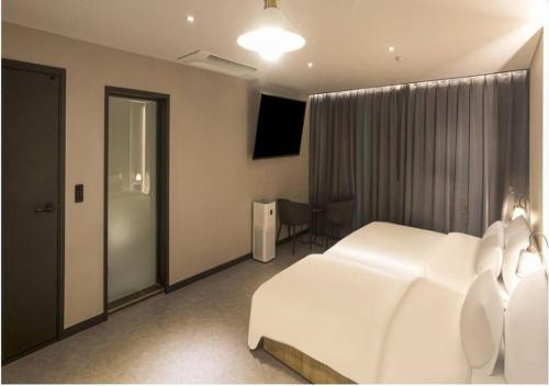 a bedroom with a white bed and a television at Day & Night Hotel in Incheon