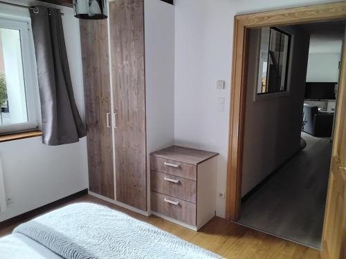 a bedroom with a door and a dresser and a mirror at Appartement au cœur du kochersberg in Kienheim