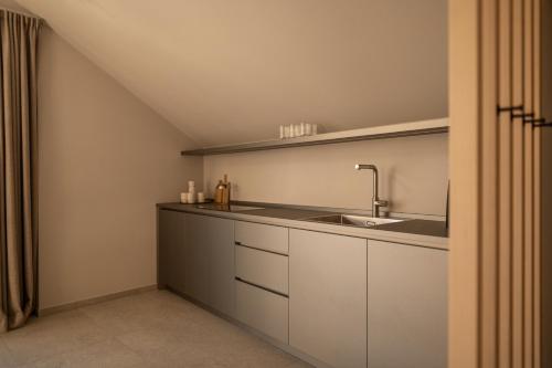 a kitchen with white cabinets and a sink at Calva B&B Apartments in Malles Venosta