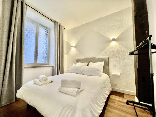 une chambre avec un lit blanc avec des serviettes dessus dans l'établissement Les Logis d'Esmeralda-Des appartements au charme intemporel, à Romorantin-Lanthenay