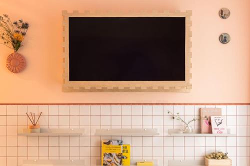 a flat screen tv on a wall above a sink at Wolne Pokoje I Boutique Apartments in Wrocław