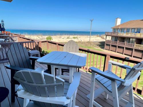 a table and chairs on a deck with the beach at Escape OBX in Kitty Hawk