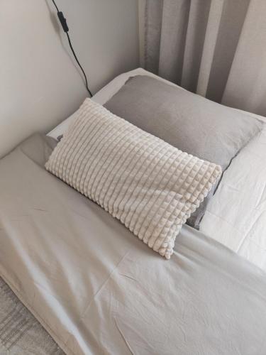 a white bed with a pillow on it at Honkatilat majoitus as 4 in Kajaani