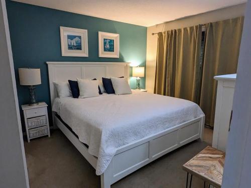 - une chambre avec un lit blanc et un mur bleu dans l'établissement South Village 7, à Glen Arbor