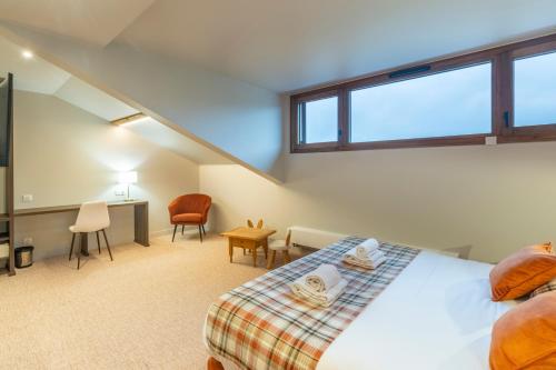 a bedroom with a bed and a desk and chairs at Hotel Le Bois Joli in Bernex