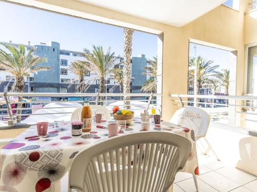 d'une table et de chaises sur un balcon avec des palmiers. dans l'établissement Apartment La Palme d'Or-21 by Interhome, à Agde