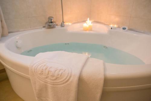 una vasca da bagno con due asciugamani e due candele di Romantic Hotel Furno a San Francesco al Campo