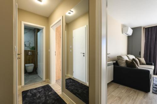a bathroom with a mirror and a living room at City Apartments 4 in Velingrad
