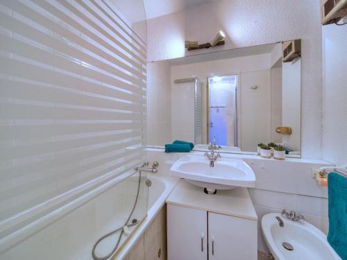 une salle de bain blanche avec un lavabo et une baignoire dans l'établissement Studio Soyouz Vanguard-103 by Interhome, au Corbier