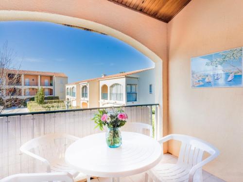 une table blanche avec un vase de fleurs sur un balcon dans l'établissement Apartment Les Canoubiers III by Interhome, à La Londe-les-Maures