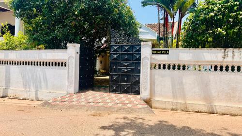 a white fence with a gate in front of a house at Shehan Villa in Beruwala