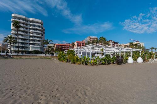a white greenhouse on the beach next to a building at Torremolinos 5 Rooms Junto al Mar in Torremolinos
