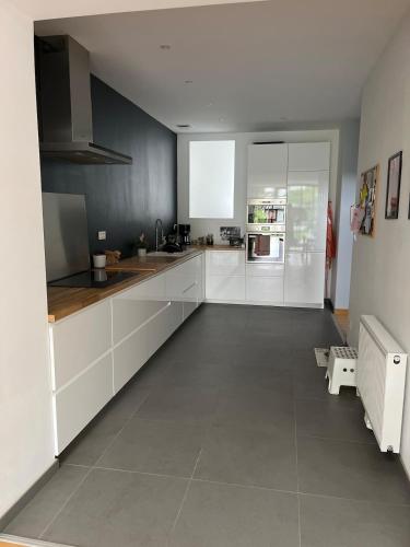 Il comprend une cuisine avec des placards blancs et un grand carrelage. dans l'établissement Maison à 5 minutes de Lille, à Saint-André