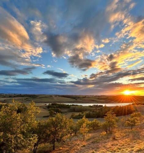 un coucher de soleil sur un champ d'arbres et une rivière dans l'établissement La bergerie - Paisible vue lac et montagne, à Molleville
