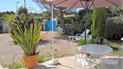 un patio avec une table, des chaises et un parasol dans l'établissement Les Mathes La Palmyre - MAISON CHARENTAISE DE CHARME - CALME -CAMPAGNE, aux Mathes