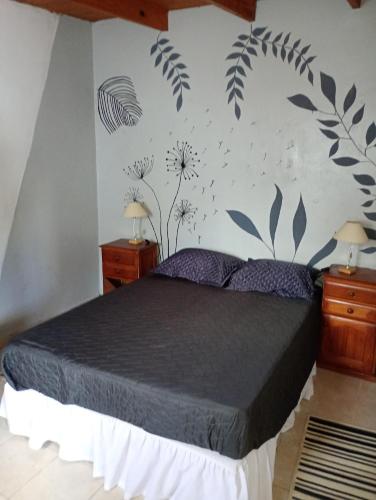 a bedroom with a bed with flowers on the wall at Casita en las sierras in Huerta Grande