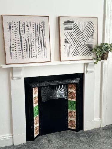 a fireplace with two framed art above it at Longsands Apartment, Tynemouth Luxury Coastal Retreat in Tynemouth