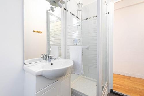 une salle de bain blanche avec un lavabo et une douche dans l'établissement GuestReady - Comfortable retreat near Le Marais, à Paris