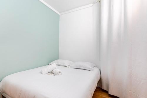 - une petite chambre avec un lit blanc et 2 oreillers dans l'établissement GuestReady - Comfortable retreat near Le Marais, à Paris