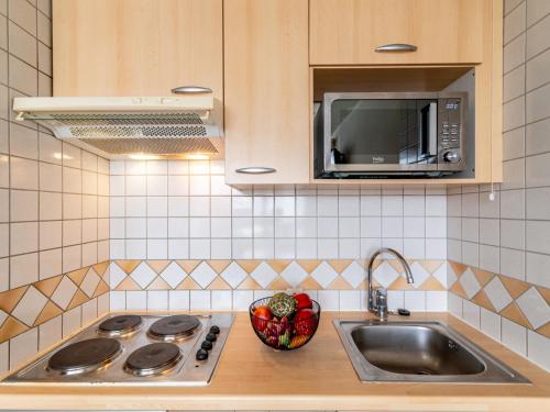une cuisine avec un évier et un micro-ondes dans l'établissement Studio Home Club - Lavachet-13 by Interhome, à Tignes