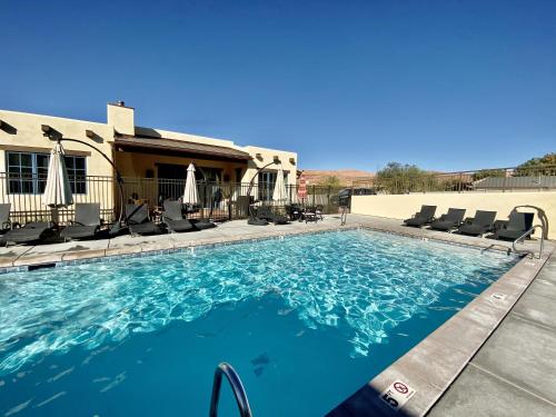 a swimming pool with chairs and a house at New Lodge In The Heart Of Moab, Utah in Moab