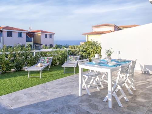 a patio with a table and chairs on the grass at Apartment La casa all'angolo by Interhome in Valledoria