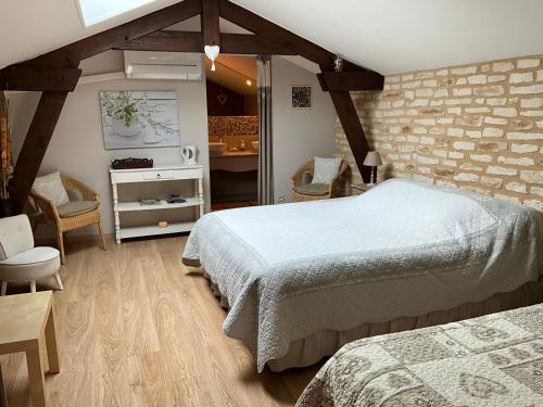 a bedroom with two beds and a brick wall at Le Moulin de Mayence in Plazac