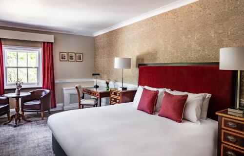a hotel room with a large bed and a desk at Chilston Park Hotel in Maidstone