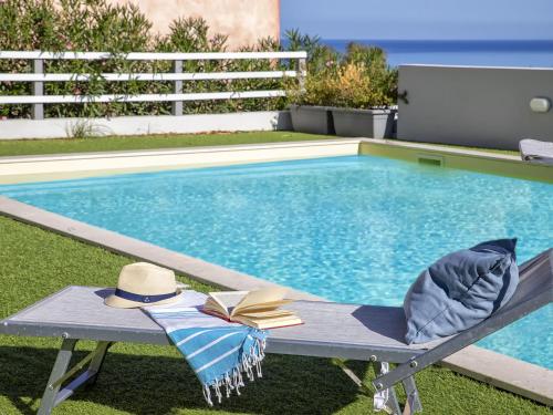 a hat and a book sitting on a bench next to a swimming pool at Apartment La terrazza sulla piscina by Interhome in Valledoria