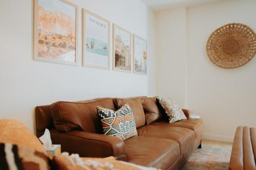 a brown leather couch in a living room with pictures on the wall at Terracotta Suite at ArnoTriplex! Hot Tub and Pet Friendly! in Albuquerque