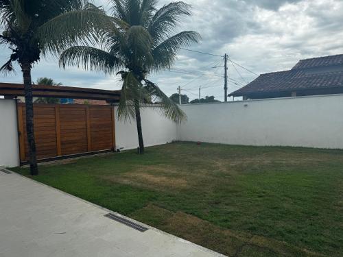 a backyard with two palm trees and a fence at Casa Jubarte in Alcobaça
