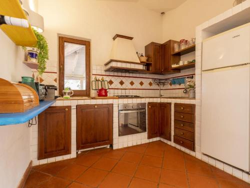 a kitchen with wooden cabinets and a white refrigerator at Villa La Giulia Porto Cervo by Interhome in Arzachena