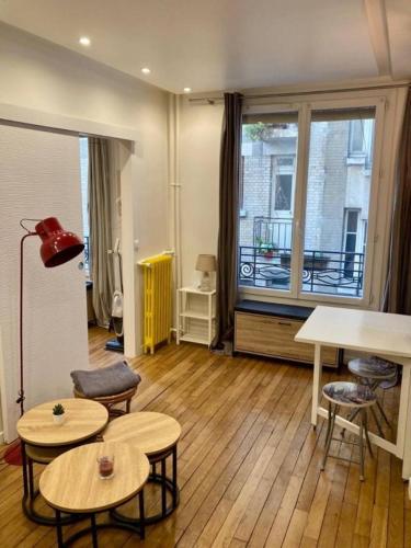 un salon avec des tables et une grande fenêtre dans l'établissement Appartement Paris 15, à Paris