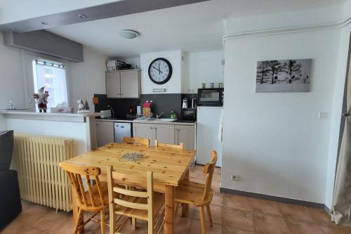 une cuisine avec une table en bois et une horloge au mur dans l'établissement 6-bed apartment close to the slopes, à Briançon
