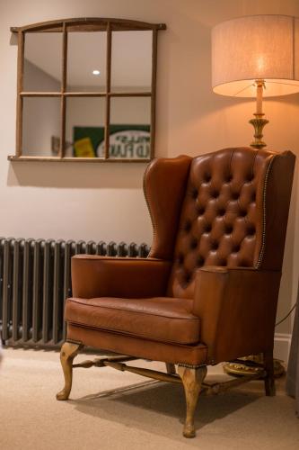 a brown leather chair in a room with a lamp at The Redan Inn in Chilcompton