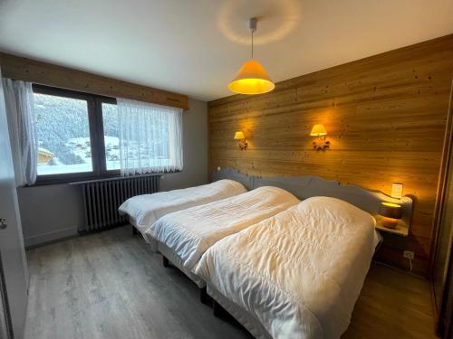 - 2 lits dans une chambre avec un mur en bois dans l'établissement GROTTE AUX FEES D, appartement 6 pers, skis aux pieds, à La Clusaz