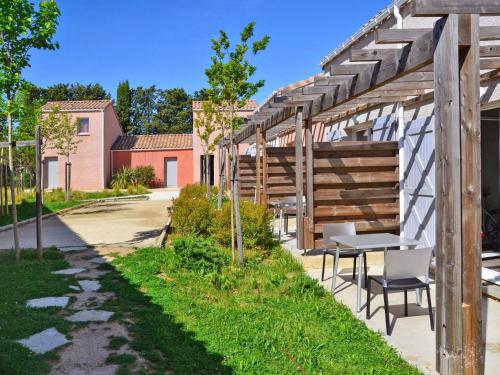 une pergola en bois avec une table et des chaises sous celle-ci dans l'établissement Holiday Home Domaine de Bacchus-Séjour-Galerie 4 pers by Interhome, à Saint-Christol