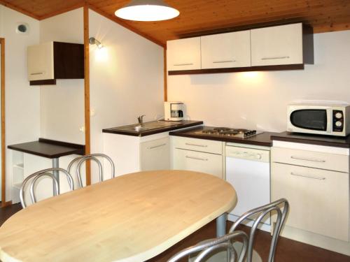a kitchen with a wooden table and a microwave at Holiday Home Les Hameaux de Miel-Chalet 4 pers- by Interhome in Beynat