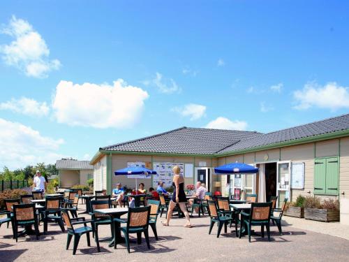 a woman walking past a patio with tables and chairs at Holiday Home Les Hameaux de Miel-Chalet 4 pers- by Interhome in Beynat