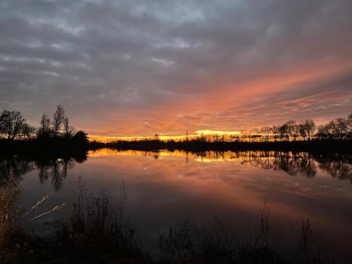 a view of a lake with the sunset in the background at L'ile chaumette in Épervans