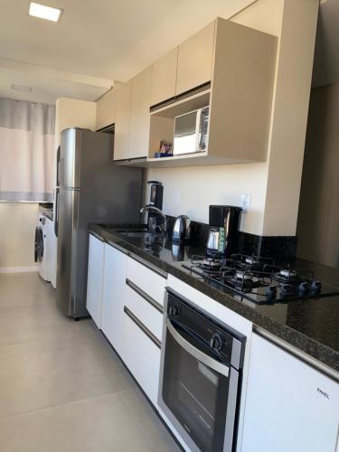 a kitchen with a stove and a refrigerator at Dallas apartamentos na Via Gastronômica-Estacionamento-Amplos e equipados-Wifi in Bento Gonçalves