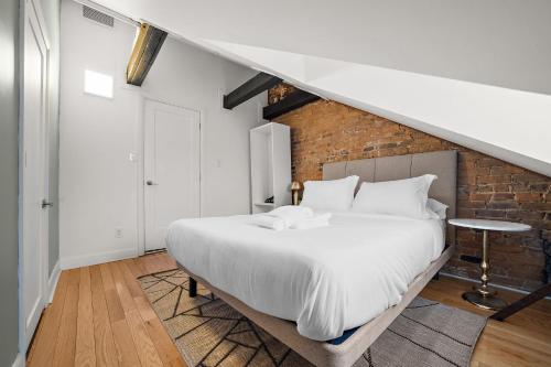 a bedroom with a white bed and a brick wall at The Ontario Loft Suites in Montréal