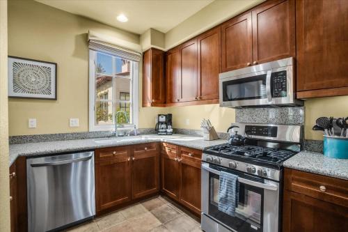 a kitchen with wooden cabinets and stainless steel appliances at Legacy Villas Hideaway overlooking Main Pool #A in La Quinta
