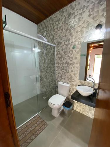 a bathroom with a shower and a toilet and a sink at Pousada Portal do Cerrado in Pirenópolis