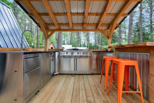 an outdoor kitchen with orange bar stools in a cabin at A-Frame Retreat with Inviting Hot Tub in Oxford