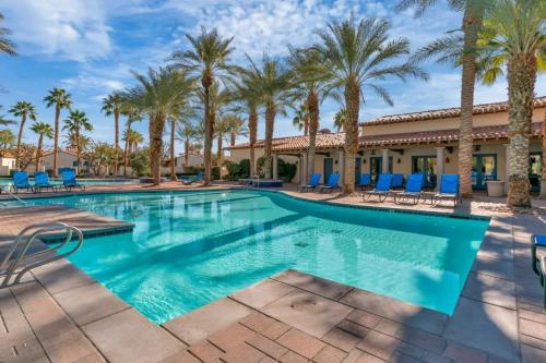 a swimming pool at a resort with palm trees at Modern LQ Getaway Steps to pool & spa #A in La Quinta